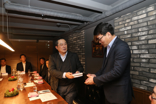 지난 26일 저녁 서울의 한 식당에서 구자열 LS그룹 회장(왼쪽)이 김우태 LS전선 부스덕트 사업부 이사에게 신규임원을 대표해 불타는 투혼 책을 선물하고 있다.  LS그룹 제공